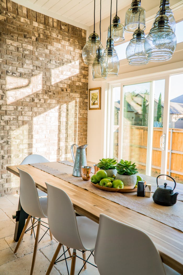 The Art of Drawing Readers In: Your attractive post title goes here Sunlit dining room with contemporary decor and a rustic brick wall, featuring stylish lighting and a wooden table.